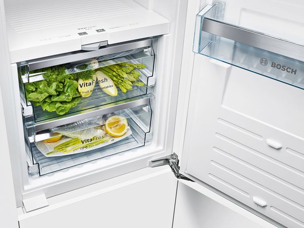 Åbent Bosch køleskab zoomet ind på to VitaFresh skuffer, fyldt med frugt, grønt og frisk fisk.