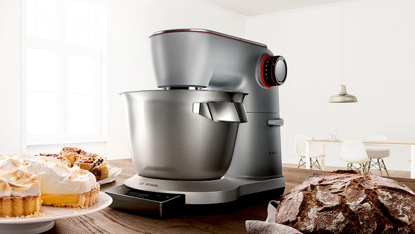 Eine silberne Bosch Küchenmaschine, umgeben von verschiedenen frischen Backwaren.