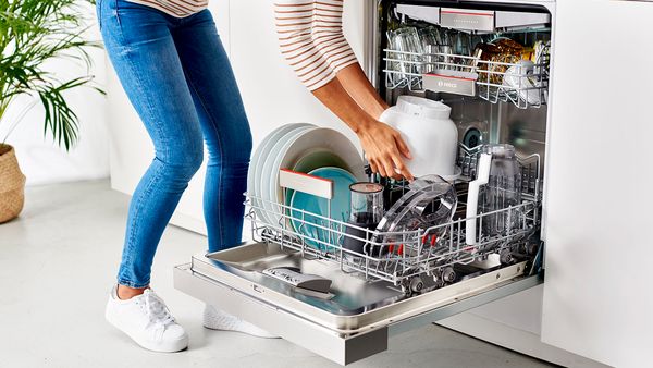 Eine Person gibt die Rührschüssel einer Bosch Küchenmaschine zur Reinigung in die Spülmaschine.