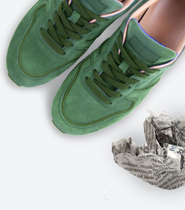 Sneakers verdi viste dall&rsquo;alto su fondo bianco, con carta accartocciata accanto