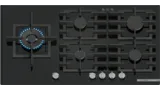 A sleek black gas cooktop with five burners, featuring a central illuminated burner and metallic knobs.